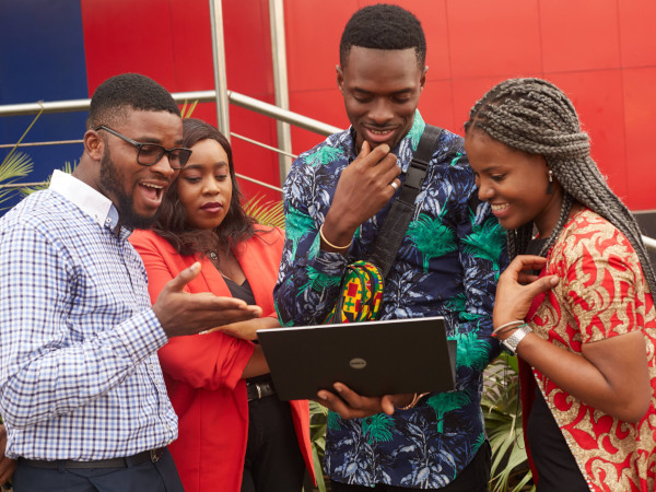Four colleagues reviewing work together on a laptop